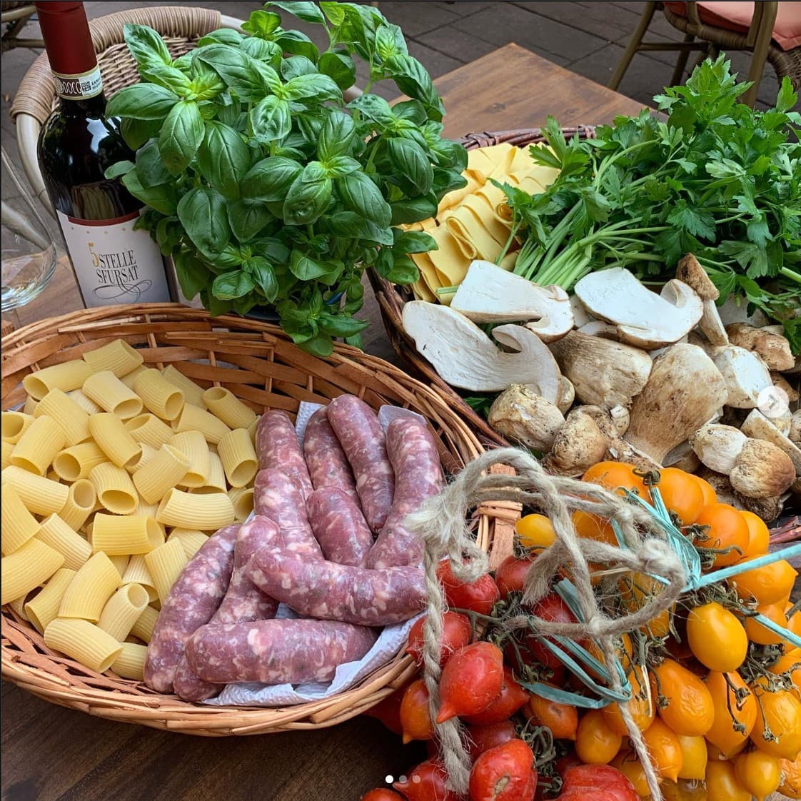 Korb mit frischer Pasta, Steinpilzen, Basilikum und sonnengereiften Tomaten